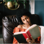 Una mujer lee un libro sentada en un sillón.